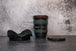 Canon 17-40 f/4.0 Camera Lens sitting vertically on the rear lens cap in the center, with the lens hood and cap sitting on either side