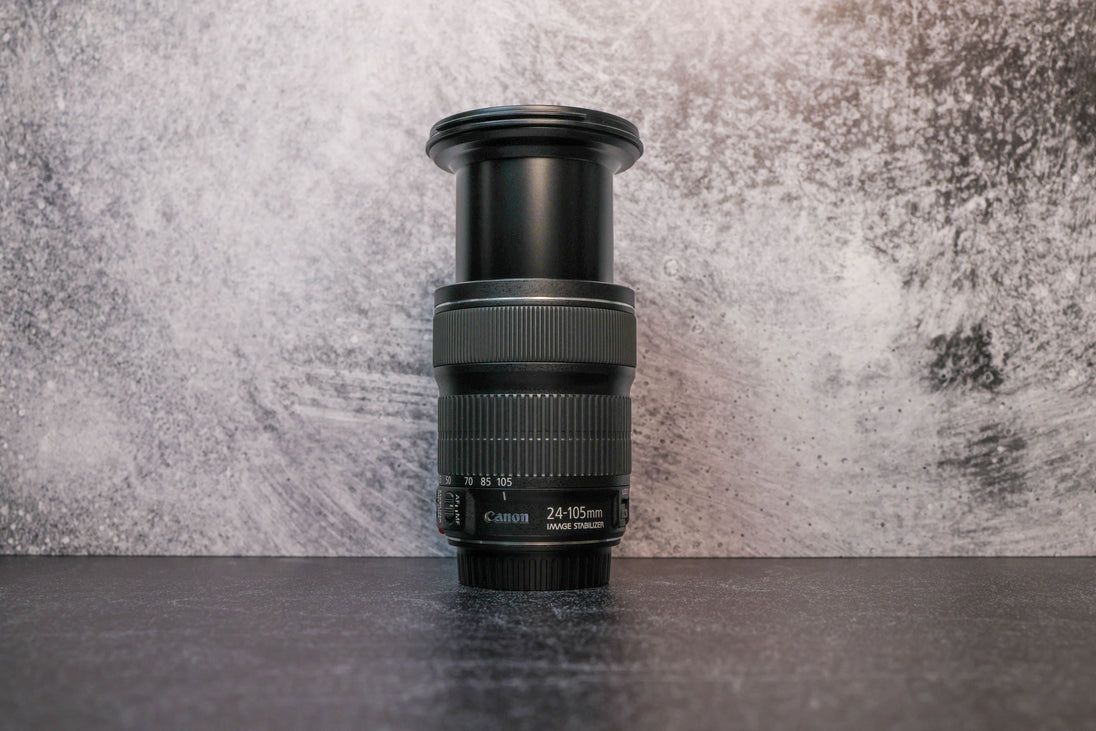 A Canon 24-105mm lens fully extended to show the zoom range sitting vertically on the rear lens cap