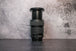 A Canon 24-105mm lens fully extended to show the zoom range sitting vertically on the rear lens cap