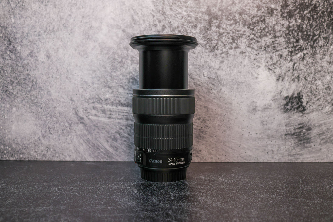 A Canon 24-105mm lens fully extended to show the zoom range sitting vertically on the rear lens cap