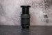 A Canon 24-105mm lens fully extended to show the zoom range sitting vertically on the rear lens cap